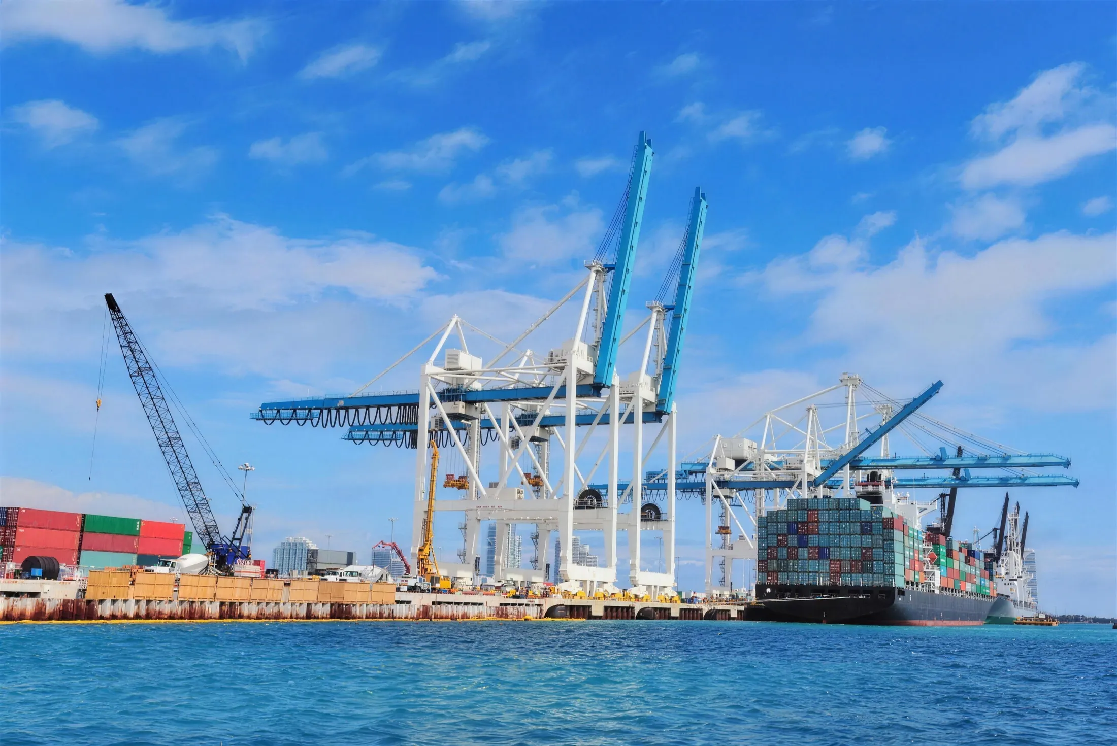 Terminal portuaria con grúas y buque atracado bajo cielo azul